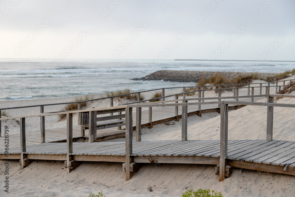 Costa Nova Beach with fine white sand and a wooden walkway at the end of a cloudy day, Aveiro, Portugal - August 2024. Costa Nova Beach with fine white sand and a wooden walkway at the end of a cloudy day, Aveiro, Portugal - August 2024.