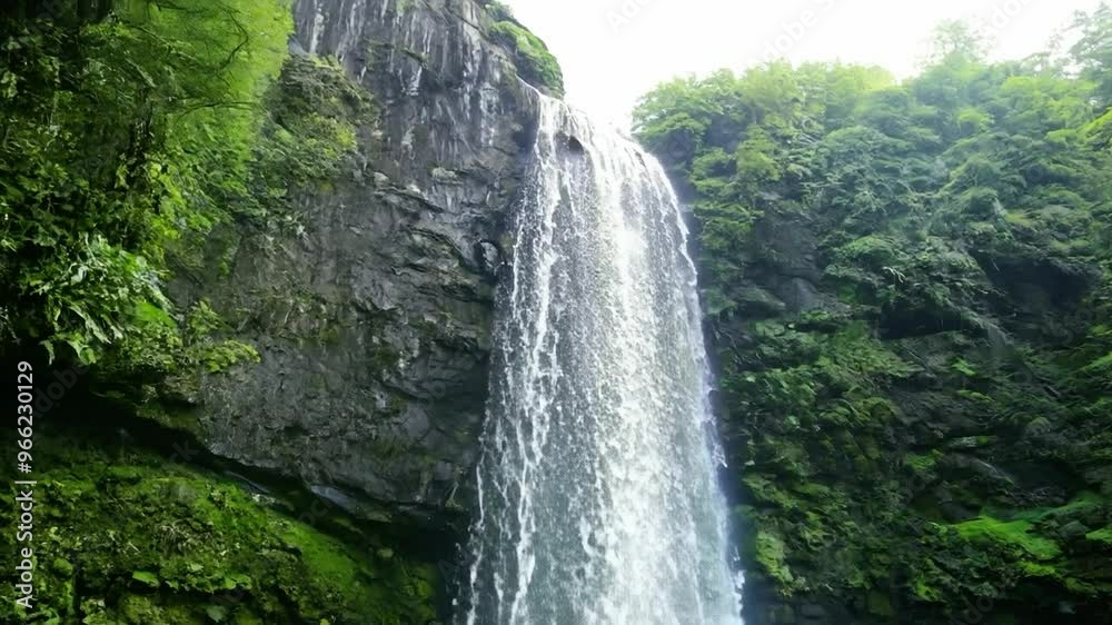 Majestic waterfall cascades down rocky cliffs surrounded by lush greenery in a serene natural setting Majestic waterfall cascades down rocky cliffs surrounded by lush greenery in a serene natural setting