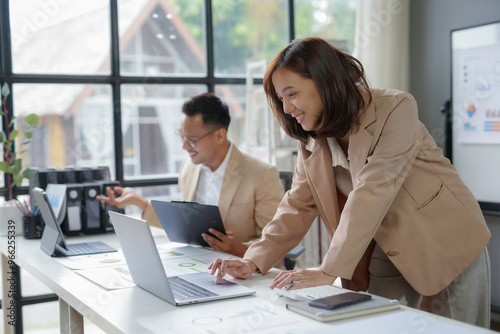 Asian businesswoman working on laptop with male colleague in office