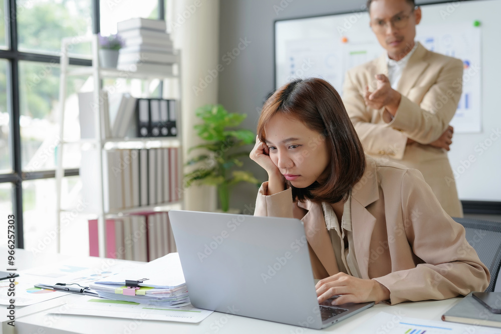 Stressed asian businesswoman working while manager is scolding her