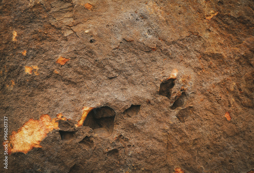 Brown grey rough stone wall with surface orange rusted and potholes for abstract background and texture, interior or exterior design. Beautiful patterns, space for work, banner, wallpaper. Close up. photo