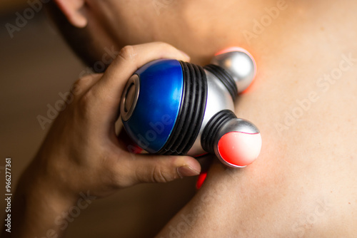 Fotografía a man gives himself a massage with a purple and blue hand massager