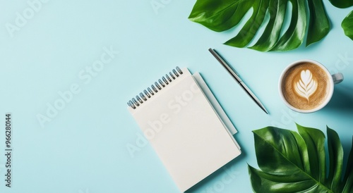 A cozy workspace featuring a notepad, pen, and coffee surrounded by greenery ...