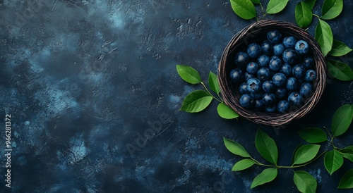 Fresh blueberries in a basket with green leaves on a dark textured background