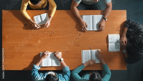 Top view of prayer reading books while prays to god at table with bible and cross placed with faith, spirituality and religion. Aerial view of diverse people holding and looking at bible. Symposium. photo