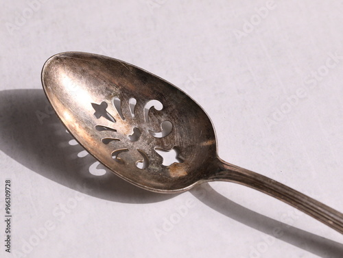 Fotografija Tarnished silver spoon with ornate cut out pattern.