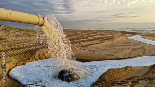 Abwasser mit weißem Schaum sprudelt aus großem Abwasserrohr am Strand in den Sand und fließt direkt ins Meer, Umweltschutz, Umweltverschmutzung, Abwasser, Gesundheit, Industrieabwasser
 photo