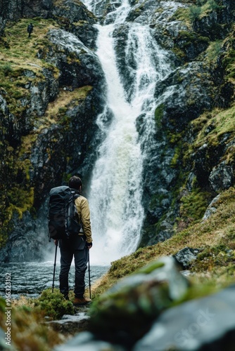 a man with a backpack standing in front of a waterfall