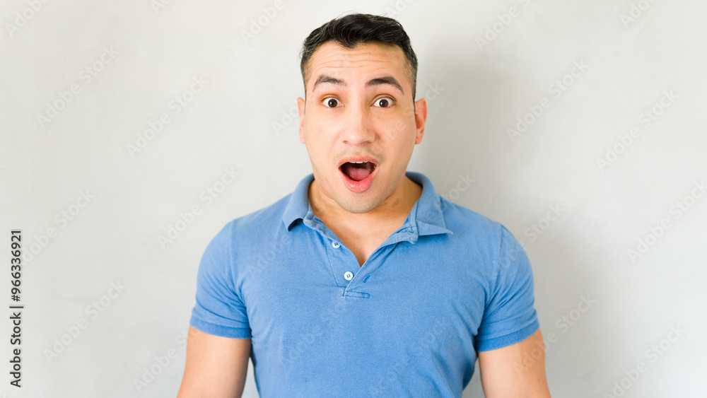 Surprised young man striking a pose against a white backdrop Surprised young man striking a pose against a white backdrop