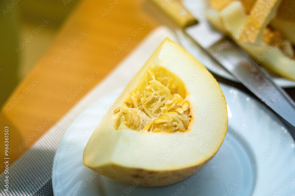 vibrant quarter of a ripe melon rests elegantly on a white ceramic plate, showcasing its bright orange flesh. The composition highlights nature's sweetness and fresh simplicity