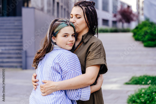 Fotografie Middle age mother hugging and kissing her teenager daughter