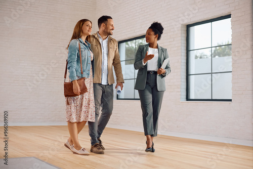 Female real estate agent showing new house to couple of potential buyers.