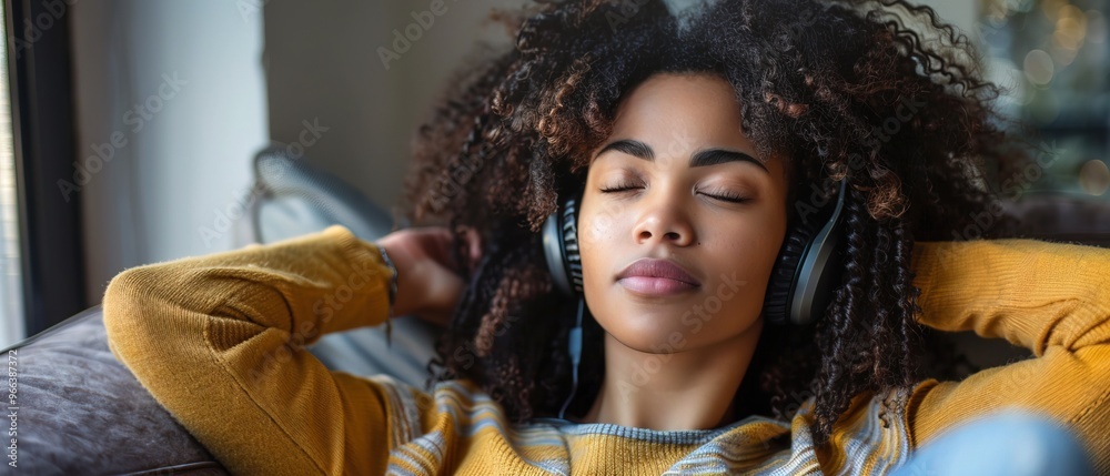 Fototapeta premium Depressed beautiful black woman listening to music on sofa, sad expression