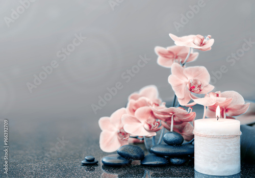 Spa background with pink orchid , candle and zen black stones on gray.
