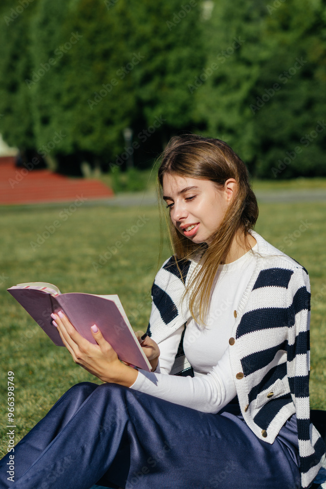 Obraz premium student girl is studying outside at the summer Holliday at the university on the green grass using laptop and taking notes