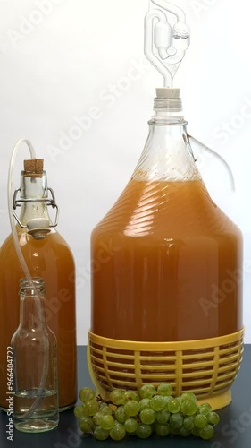 Making grape wine at home. Fermentation process. Demijohn with a fermentation tube and a bottle with a homemade airlock valve. Visible carbon dioxide bubbles. Verticasl video. photo