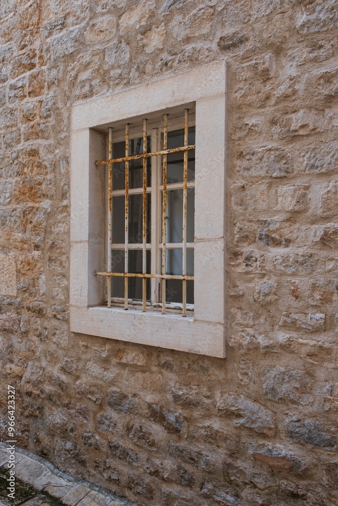 Fototapeta premium Rusty barred window on old stone wall