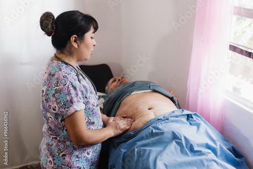 In a hospital, an elderly woman is lying on a stretcher and a nurse is performing an abdominal examination.