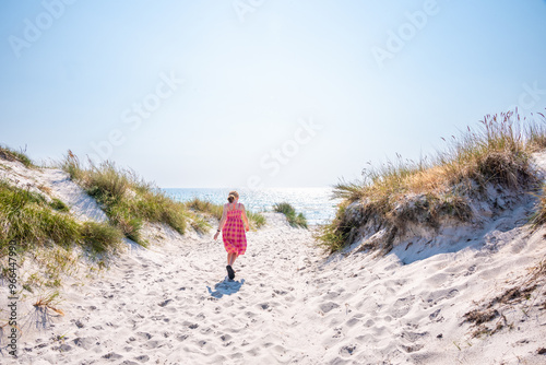 Summery scene of a girl walking on an empty beach in bright sunshine. Photographed in Falsterbo, Sweden