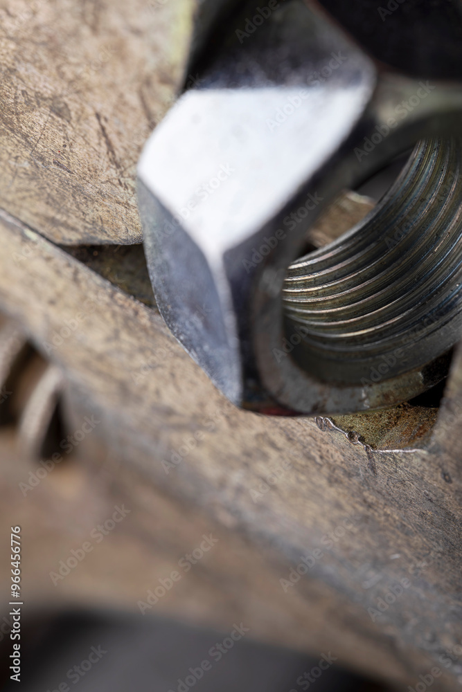 Adjustable wrench holding metal nut on dark background. Macro shot of tool and hardware for construction and repair. Adjustable wrench holding metal nut on dark background. Macro shot of tool and hardware for construction and repair.