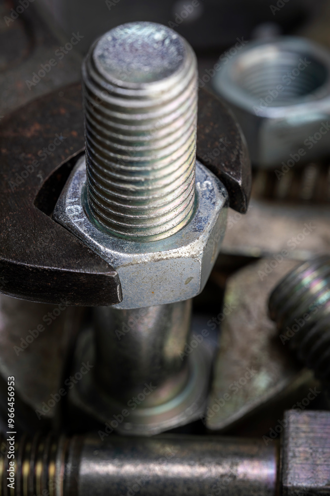 Wrench tightening metal bolt surrounded by nuts and bolts. Macro shot of construction and repair tools. Wrench tightening metal bolt surrounded by nuts and bolts. Macro shot of construction and repair tools.