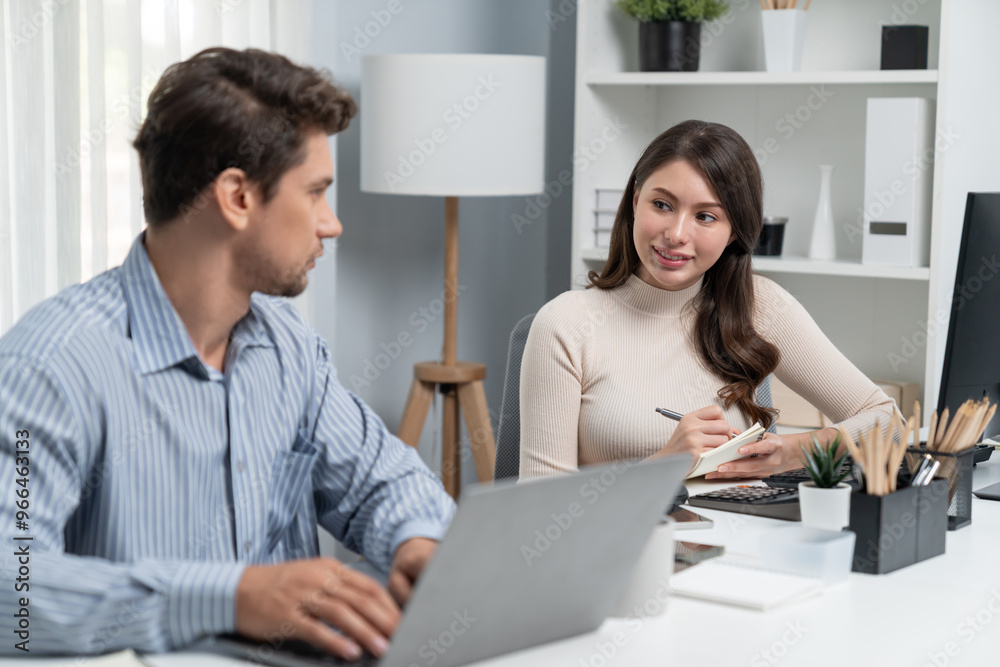 Smart manager talking to woman coworker while typing on laptop asking information data research project for business analysis report on desk at side view at modern office in morning time. Postulate. Smart manager talking to woman coworker while typing on laptop asking information data research project for business analysis report on desk at side view at modern office in morning time. Postulate.