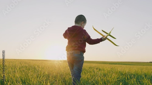 Child Boy Runs Through Park With Toy Plane His Hand Sunset Sky. Carefree Small Boy Jogging With Airplane Through Meadow. Dreaming Flights Enjoying Summer Vacation. Steadicam Shot.