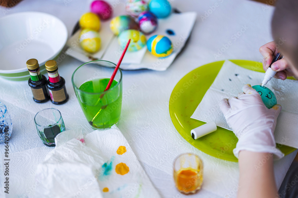 Close-up view of child drawing on Easter egg at table with supplies for decoration. Sweden. Close-up view of child drawing on Easter egg at table with supplies for decoration. Sweden.