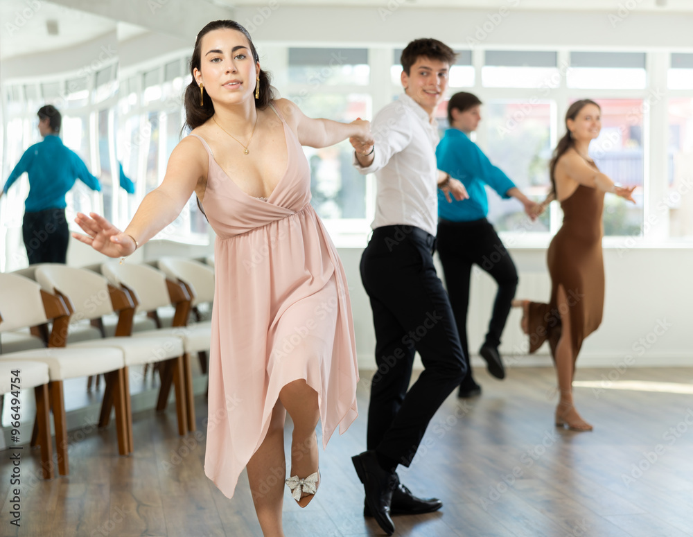 Fototapeta premium Couple of young guy and young woman dancing twist in studio