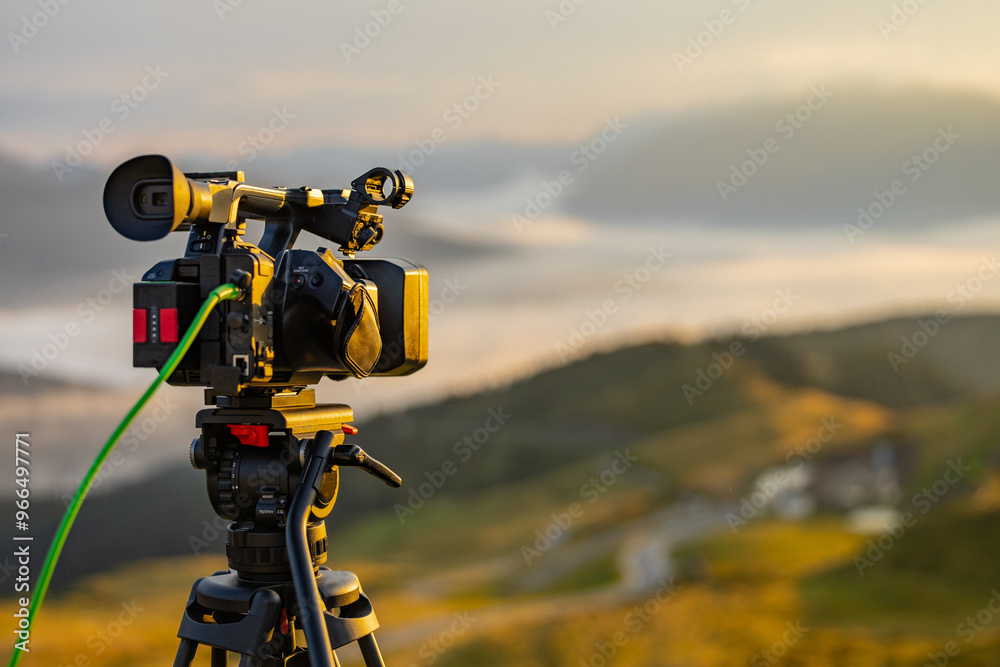 Modern video camera filming on a tripod a beautiful morning panorama. Typical work for a videographer in the morning, handheld camera with sdi signal cable in the back