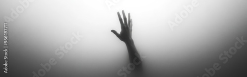 A shadowy hand reaches out through a foggy surface, evoking themes of longing or struggle.