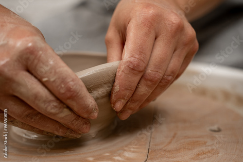 Creating a ceramic bowl by yourself in a pottery class. Wheel throwing. Learning how to model clay into different shapes with pottery wheel. photo