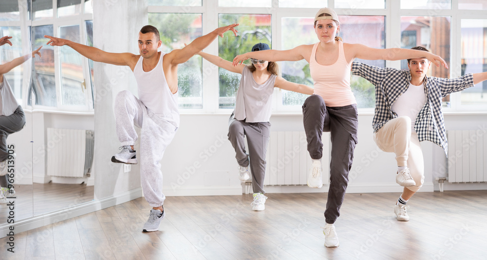 Fototapeta premium Young girl standing performs basic hip hop movements in front of group of students. Developing precise movements, rehearsing arc elements, nae nae moving