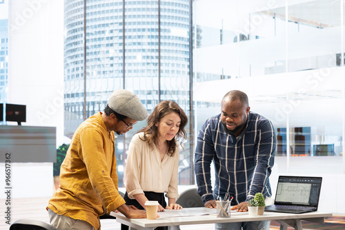 Real estate agents and client sharing property investment strategy during an office tour at a high class office building. Examining architectural plans to check the layout. Workspace relocation. photo