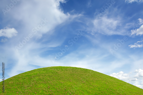 Green grassy hill under a blue sky with white clouds.