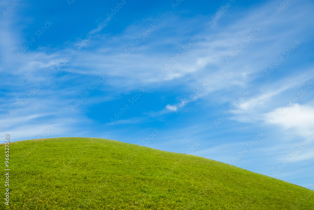 Green grassy hill against a blue sky with clouds. Green grassy hill against a blue sky with clouds.