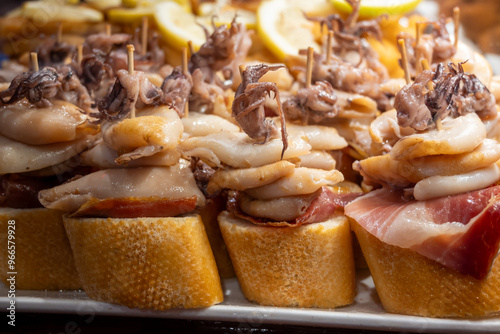 Typical snacks of Basque Country, pinchos or pinxtos skewers with small pieces of bread, fish, sea food, sweet green pepper served in bar in San-Sebastian or Bilbao, Spain photo