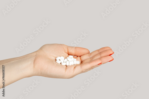 Closeup of woman hand handful of pills capsules, nutritional supplement, vitamins, medicine. Indoor studio shot isolated on gray background.