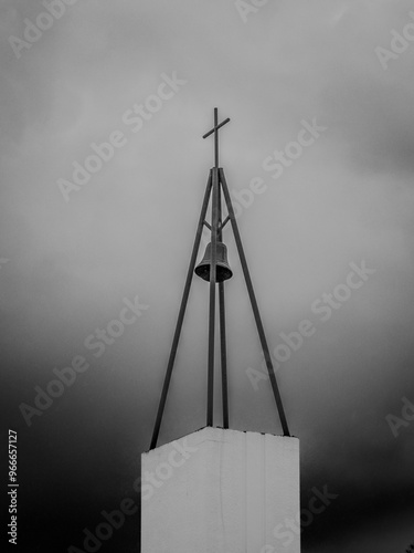 Black and white church bell under a cross with a stormy background photo