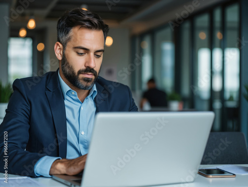 Businessman working on a laptop in a modern office, highlighting focus and professionalism. Ideal for business, corporate, or technology themes.