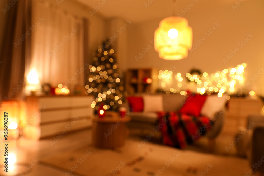 Fototapeta premium Interior of cozy living room with sofa and Christmas tree decorated for holiday at night, blurred view