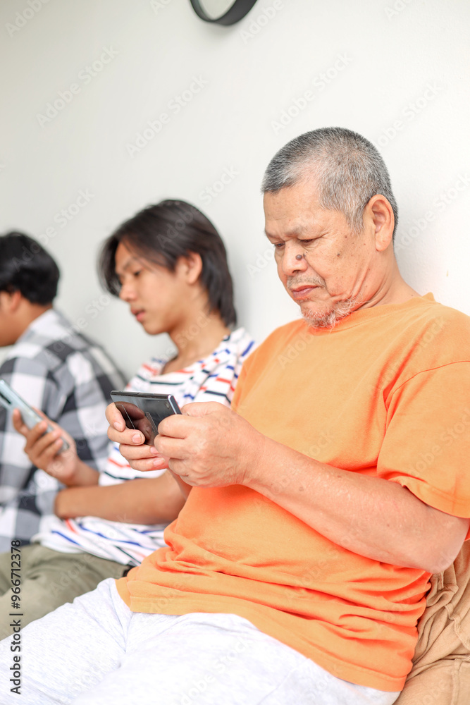 Fototapeta premium Modern Asian Father And His Two Son Using Mobile Phone Playing Games Together