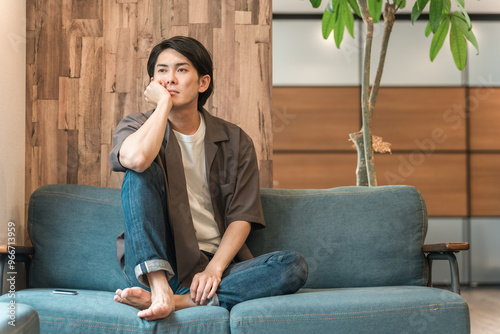 Canvastavla 家のリビングで退屈な時間を過ごす若いアジア人男性（つまらない・憂鬱・無気力・ダルい・疲労・怒る）