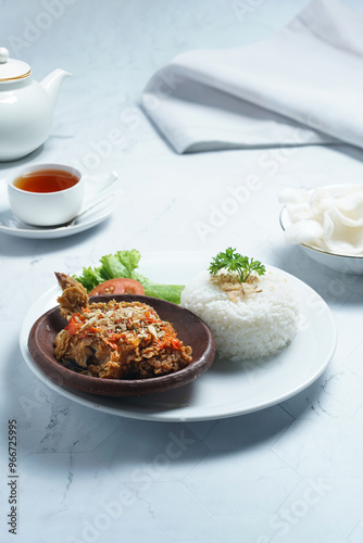 Ayam geprek is a typical Indonesian dish of fried chicken with flour that is mashed or mashed with plow chili sauce.