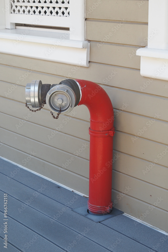 A Bright Red Fire Hydrant Attachment Installed on a Wooden Deck in an Urban Area A Bright Red Fire Hydrant Attachment Installed on a Wooden Deck in an Urban Area