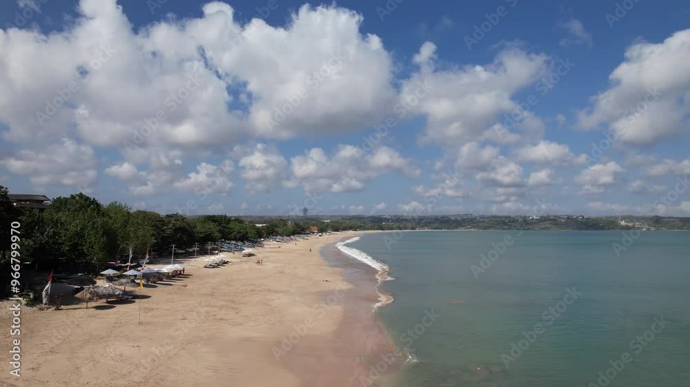 Aerial video over the Jimbaran beach at Bali, Denpasar, Indonesia during a sunny day with calming sea waves. Aerial video over the Jimbaran beach at Bali, Denpasar, Indonesia during a sunny day with calming sea waves.