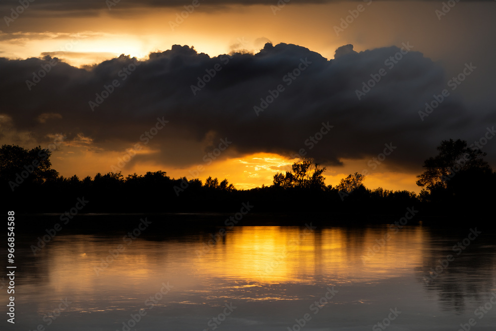 Stormy clouds over lake at sunset, showcasing climate change effects. Stormy clouds over lake at sunset, showcasing climate change effects.