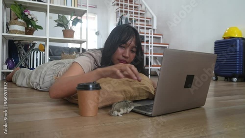 Young Asian Woman Working On Laptop Accompanied By Her Hamster At Home photo