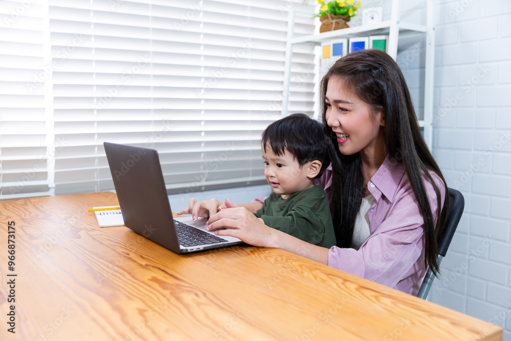 Asian businesswoman working in modern office while looking after child,teaching working and being a family care motherhood raising her kid while working with computer laptop technology Asian businesswoman working in modern office while looking after child,teaching working and being a family care motherhood raising her kid while working with computer laptop technology