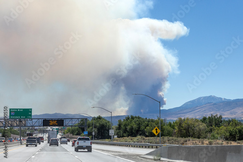 Plume of wildfire smoke from Davis fire south of Reno in the background of a freeway sign warning of fire danger